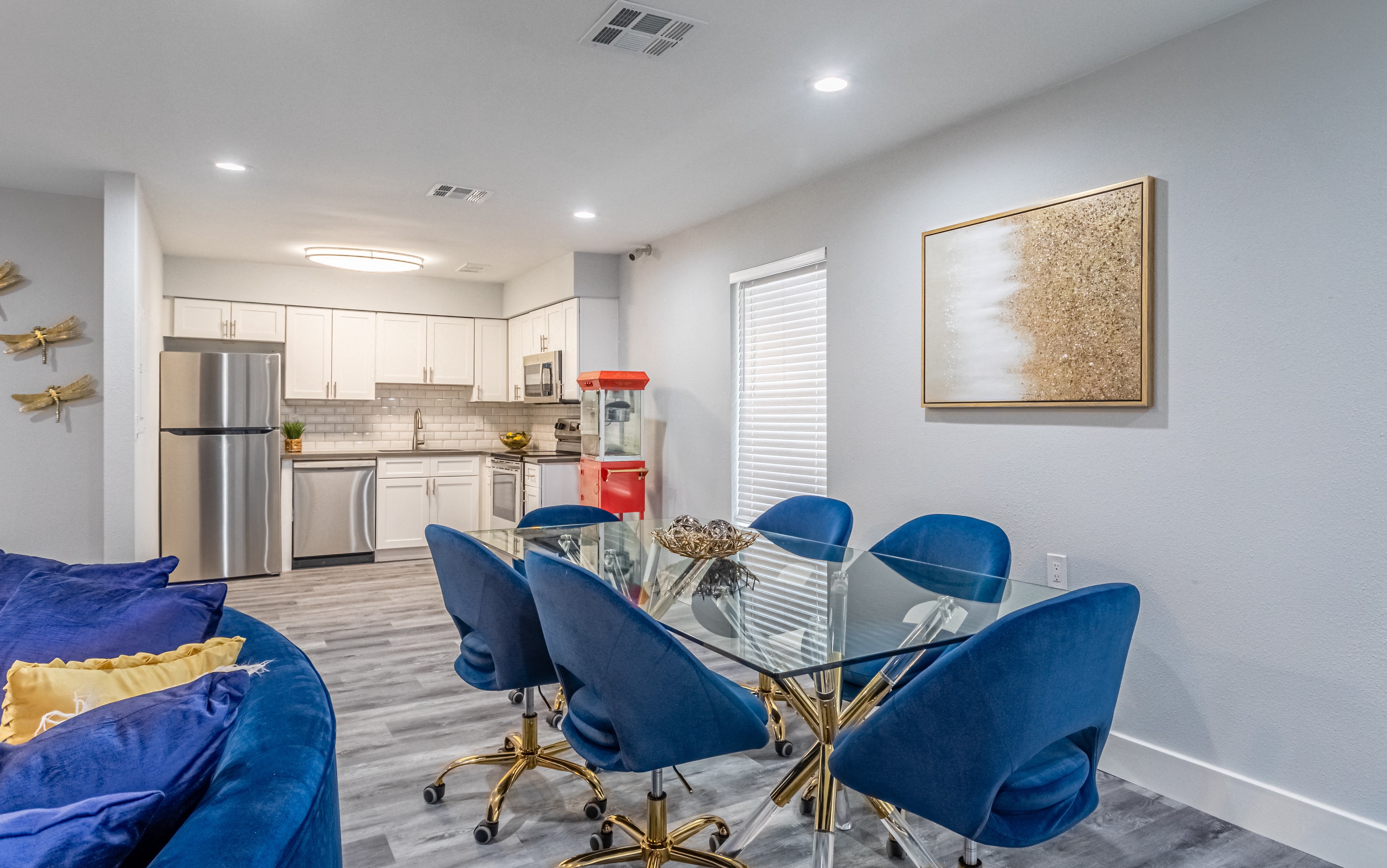 a dining room with a glass table and chairs and a kitchen